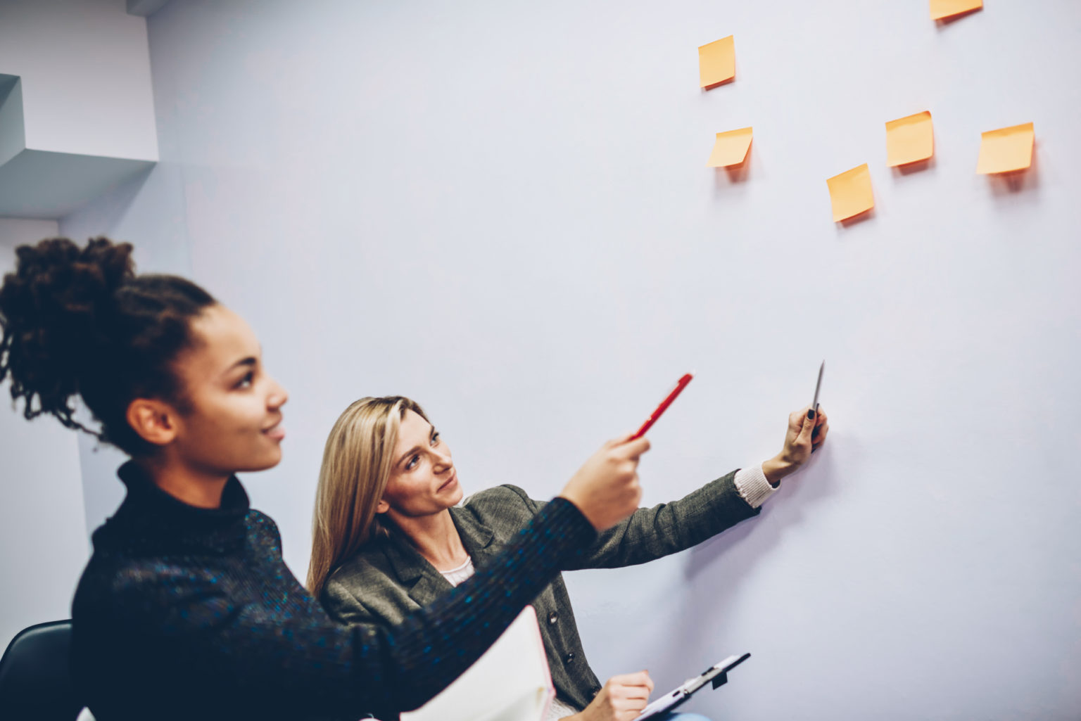 two,female,colleagues,pointing,on,stickers,with,creative,ideas,on