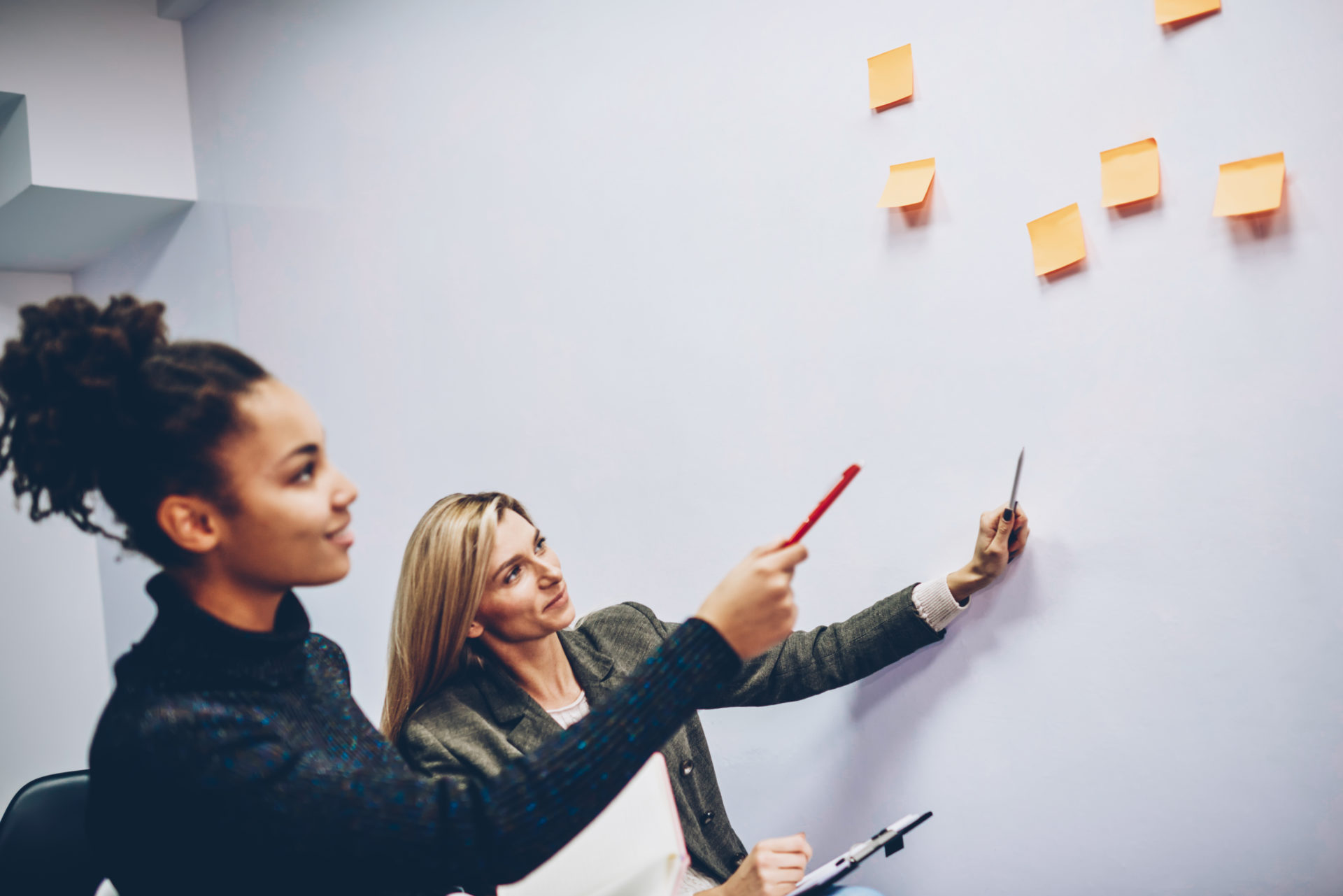 two,female,colleagues,pointing,on,stickers,with,creative,ideas,on